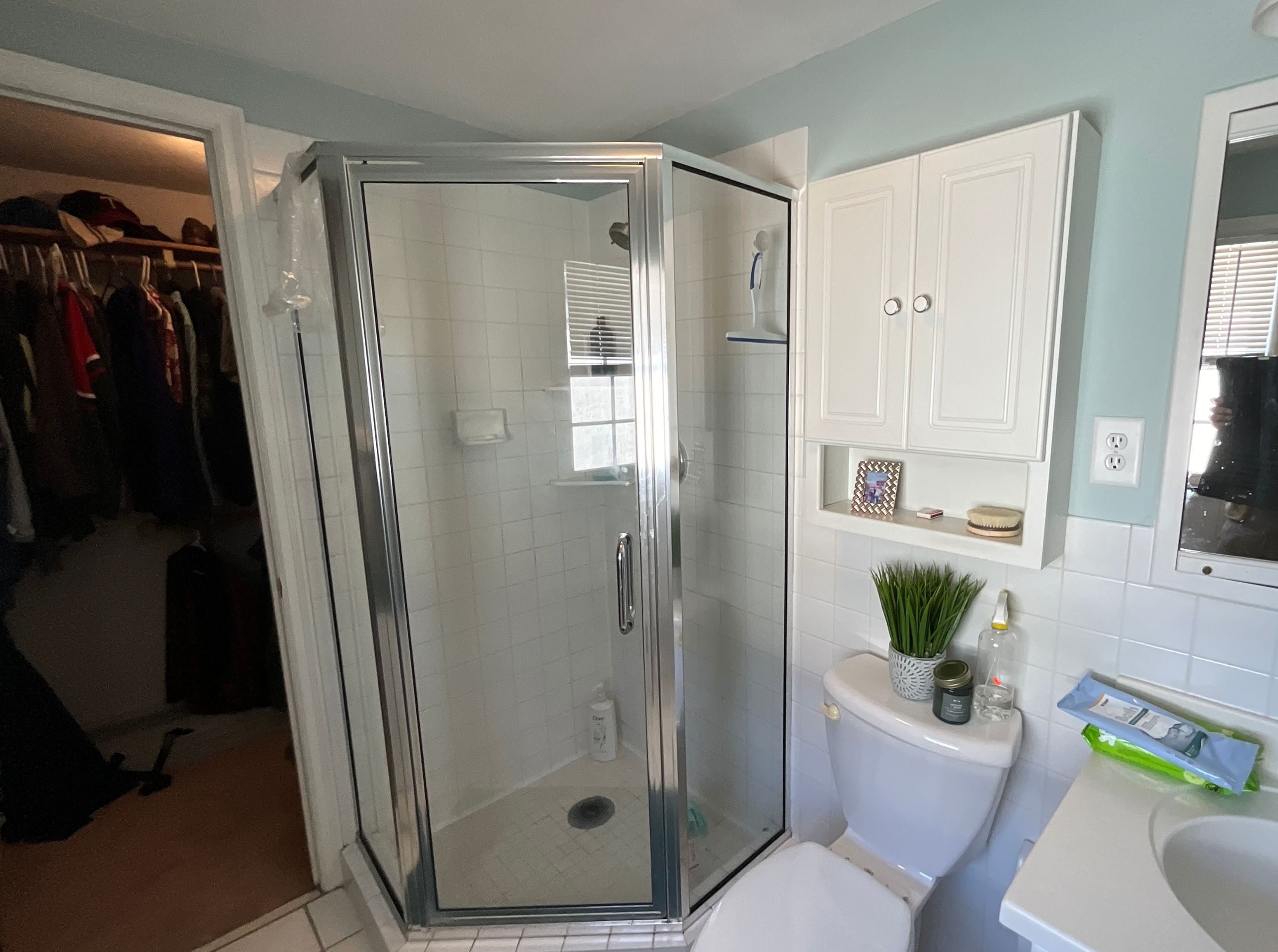 before image of primary bathroom with a corner shower and doorway to the closet
