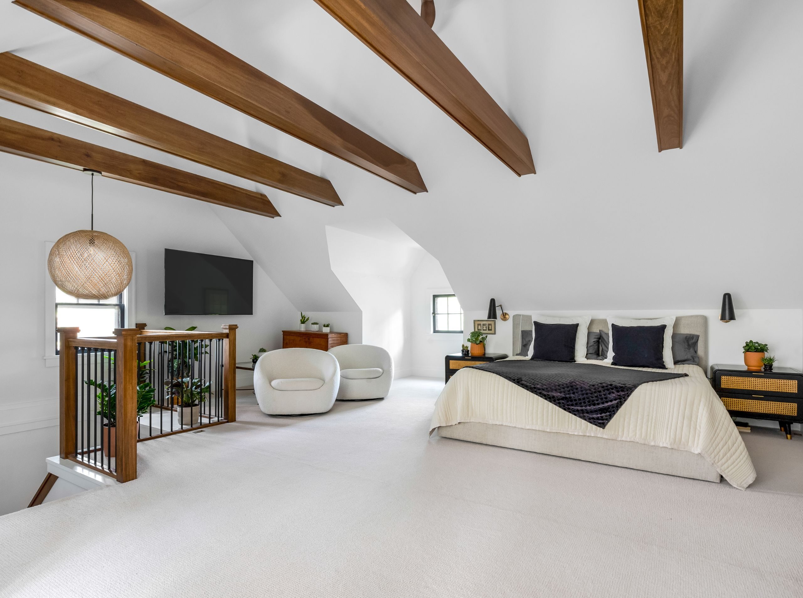 attic bedroom with white walls, deep wood beams, and layered textures