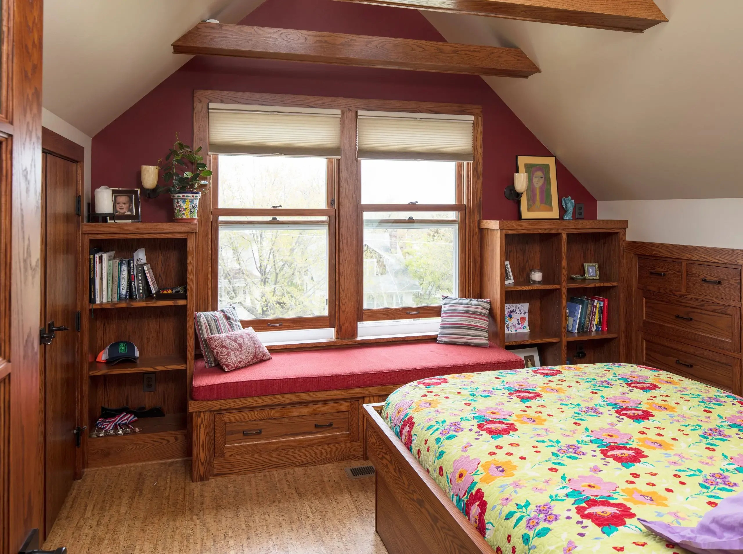 cozy attic remodel with a built in bench and bookshelves, bed with floral blanket